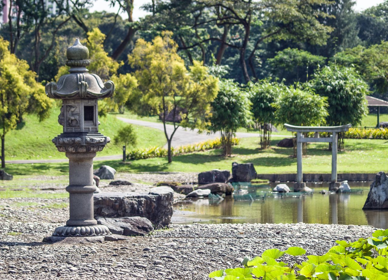 tranquil view of a japanese garden featuring a stone lantern and pond