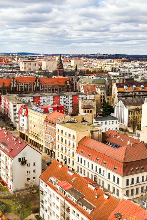 Free Aerial view of a historic European city with colorful rooftops and cloudy sky. Stock Photo