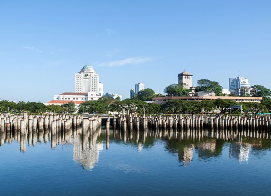 Beautiful view of Johor Bahru skyline reflecting on calm water on a sunny day.