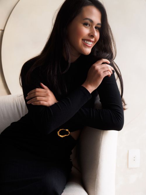 Free Stylish woman in a black dress sitting elegantly on a contemporary couch, indoors. Stock Photo
