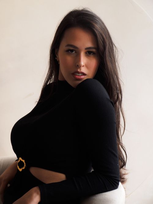 Free Portrait of a stylish woman in a black dress posing confidently indoors. Stock Photo