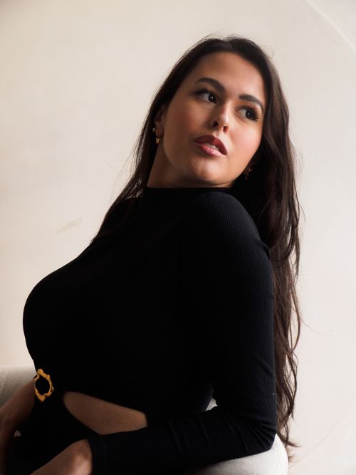 Free Sophisticated portrait of a woman in a black dress on a neutral background. Perfect for fashion and lifestyle themes. Stock Photo