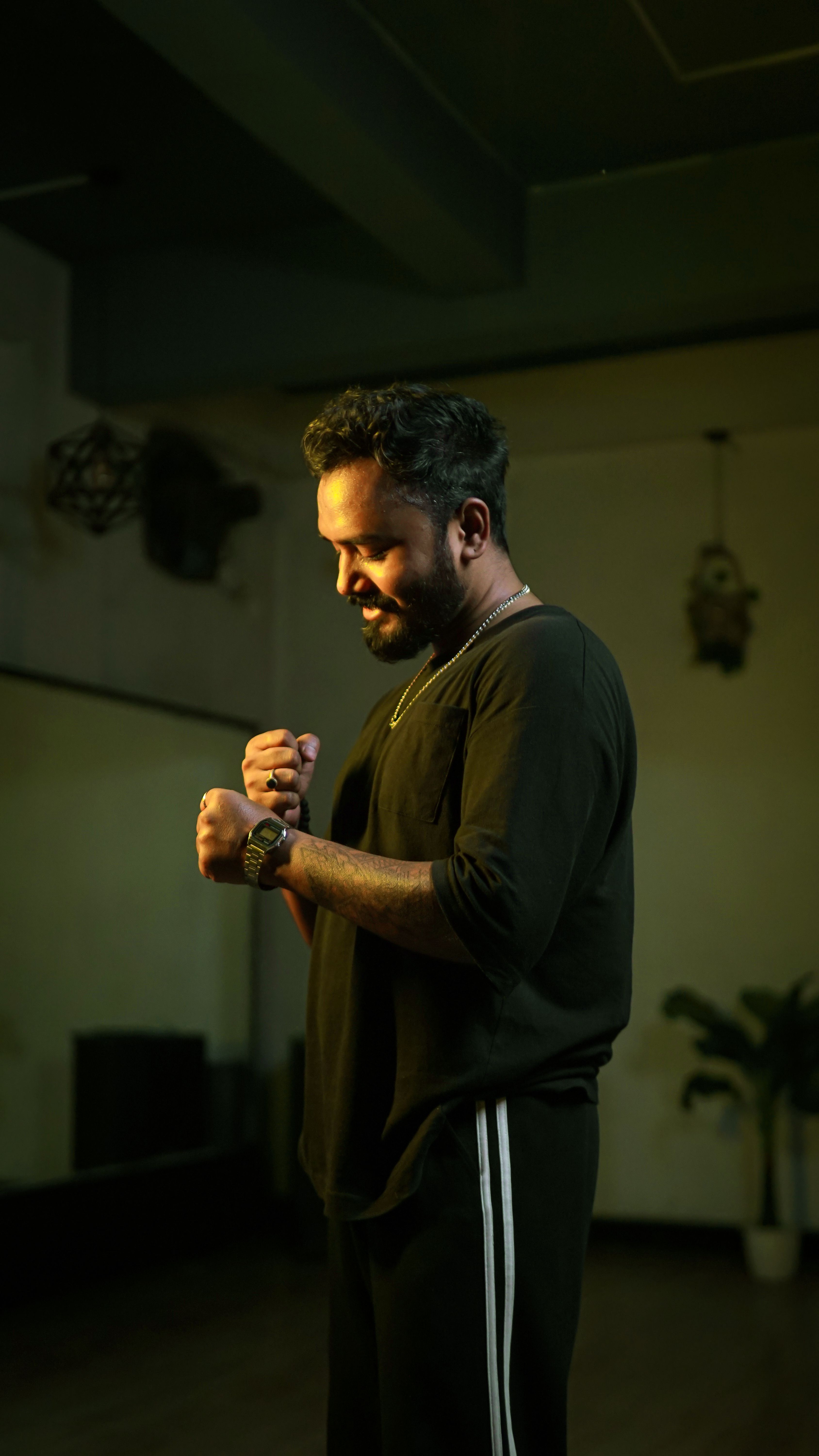 A thoughtful man posing confidently inside a dimly lit dance studio, creating a serene and introspective mood.