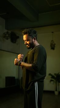 A thoughtful man posing confidently inside a dimly lit dance studio, creating a serene and introspective mood.