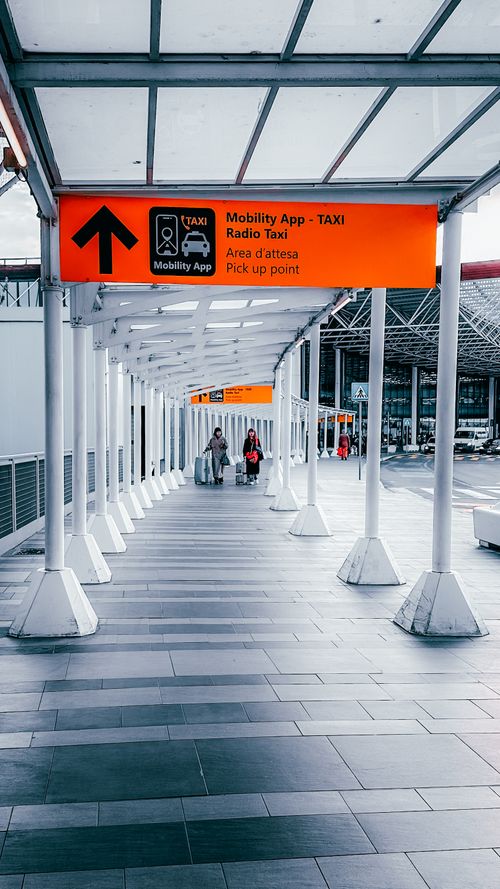 Free Modern outdoor corridor leading to a taxi pickup point in Dortmund with clear signage and travelers. Stock Photo