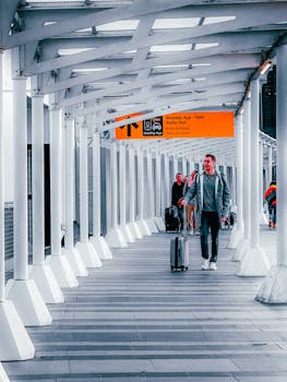 Travelers walking through a modern airport walkway with luggage, heading towards a taxi pickup point.