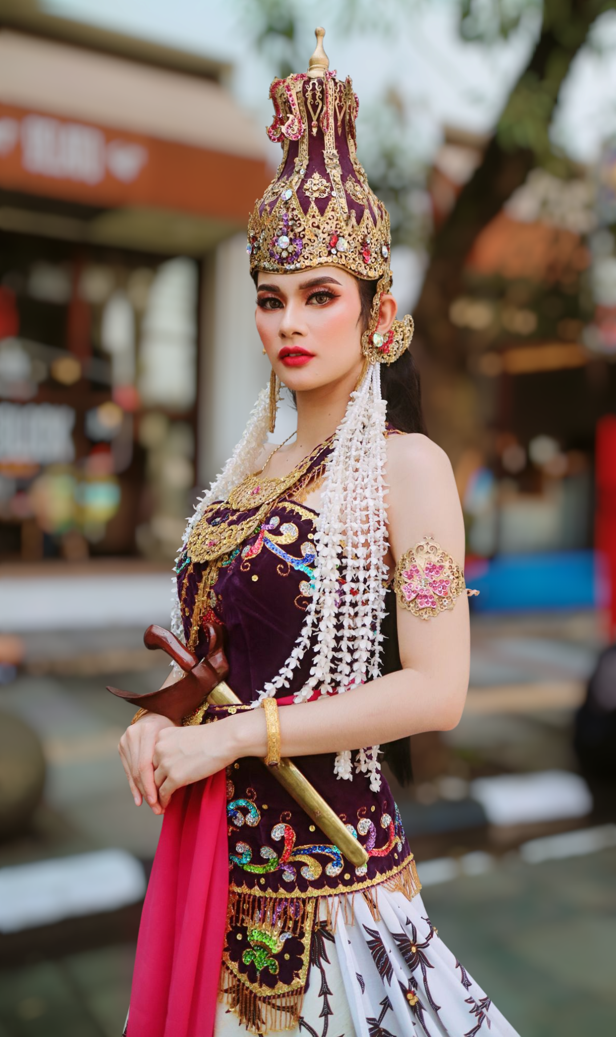 Portrait of a woman in traditional Indonesian attire, adorned with intricate jewelry and headdress.