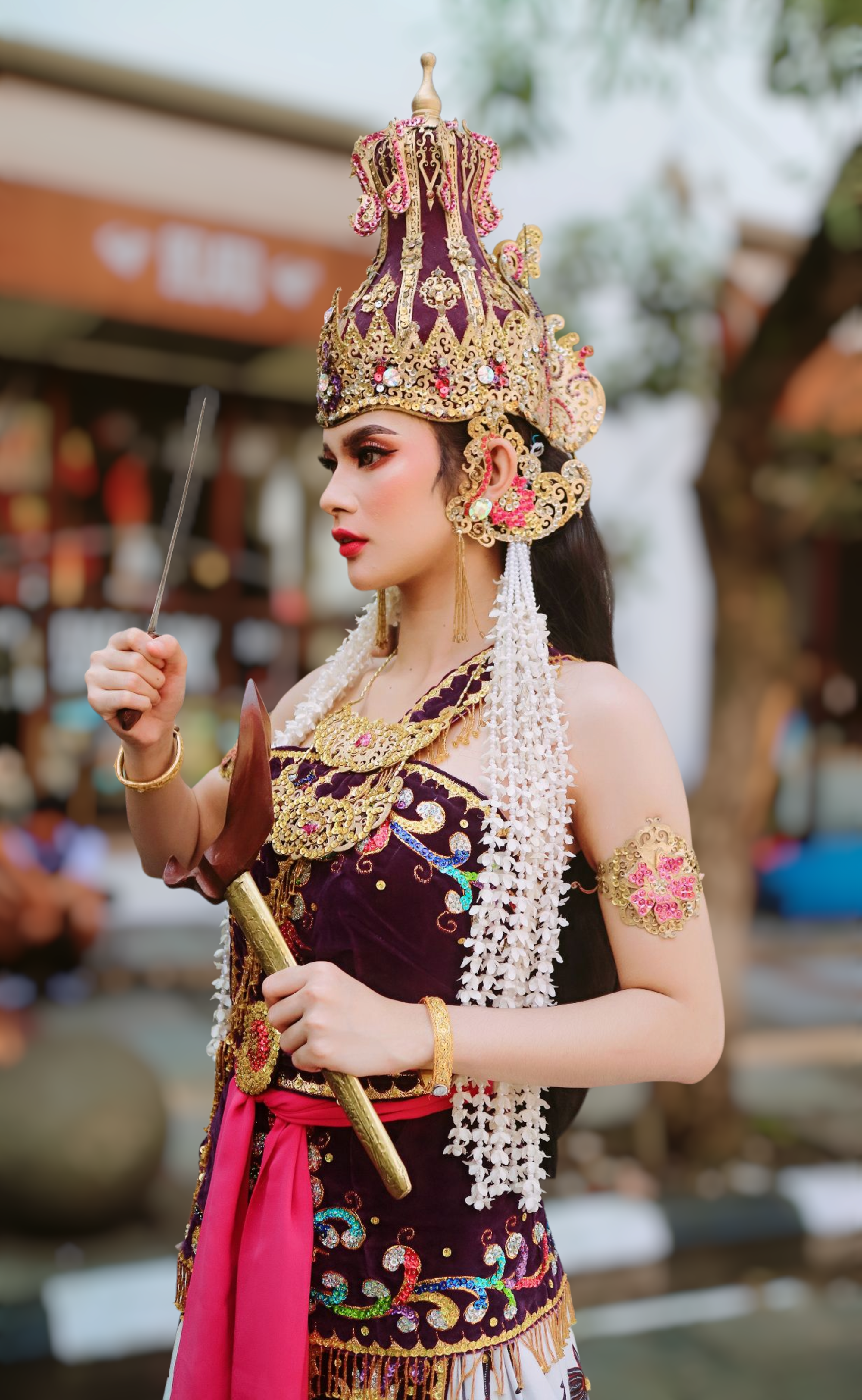 A captivating Javanese dancer in traditional attire performing outdoors during the day.