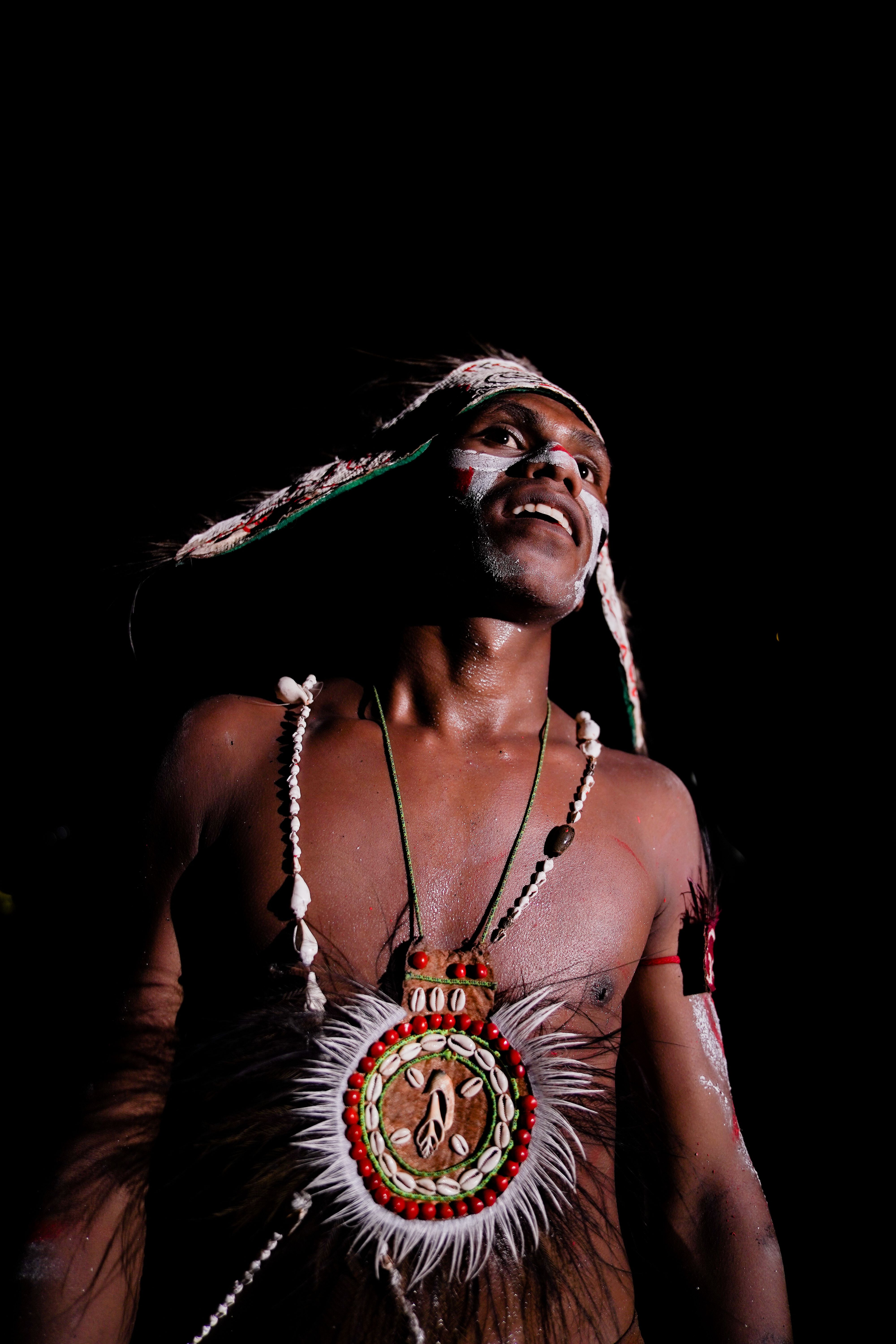 Gratis Un hombre con atuendo tribal tradicional baila bajo una iluminación vibrante. Foto de stock
