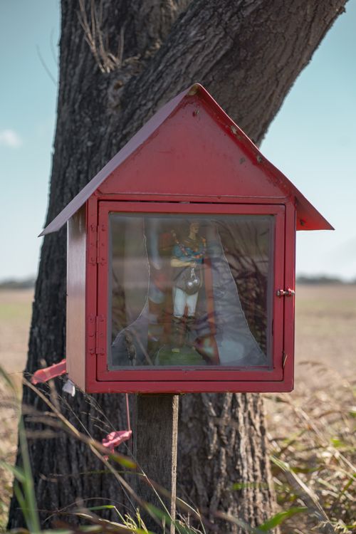 Free Red roadside sanctuary in rural Oliva, Córdoba against a tree backdrop, Argentina. Stock Photo