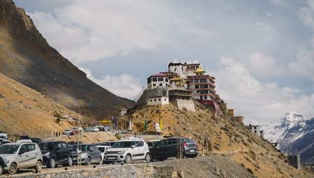 Picturesque view of Key Monastery atop a hill in Spiti Valley, with cars and mountains.