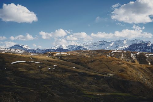 Free Majestic snow-capped mountains with clear skies and rolling hills. Stock Photo