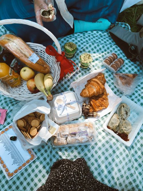 Free Overhead view of a summer picnic with pastries, fruits, and snacks on a checkered blanket. Stock Photo