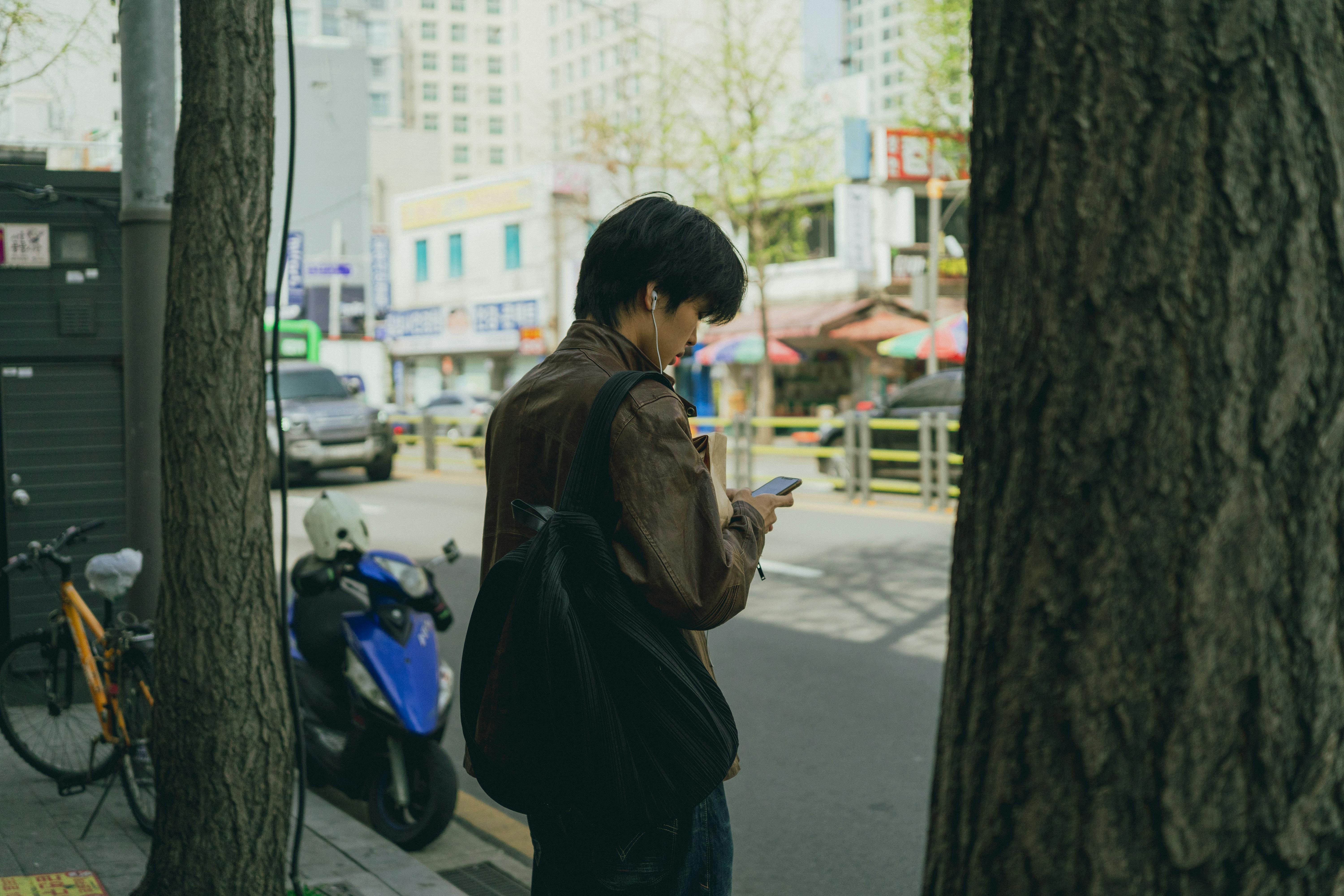 grátis Um jovem usando seu smartphone enquanto caminha por uma rua movimentada em Seul, Coreia do Sul. Foto profissional