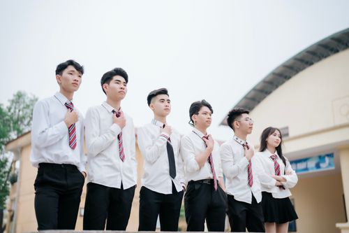 Free Group of young adults wearing school uniforms posing confidently outdoors in a courtyard. Stock Photo
