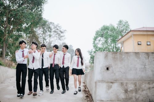 Free A group of teenagers walking together in school uniforms, enjoying a bright day outdoors. Stock Photo