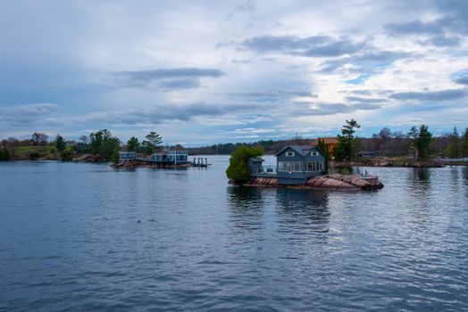 Tranquil view of charming lake houses on rock islands under a cloudy sky in Ontario, Canada.