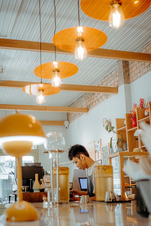 Free Warm and inviting cafe scene featuring a barista with modern decor and lighting. Stock Photo