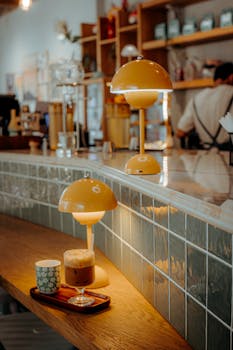 Warm cafe interior with stylish lighting and coffee on counter.