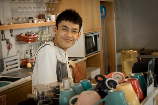 A friendly barista smiling behind the counter in a cozy coffee shop.