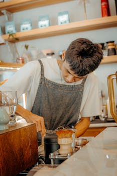 Young barista preparing coffee in a stylish cafe with a focus on craft and detail.