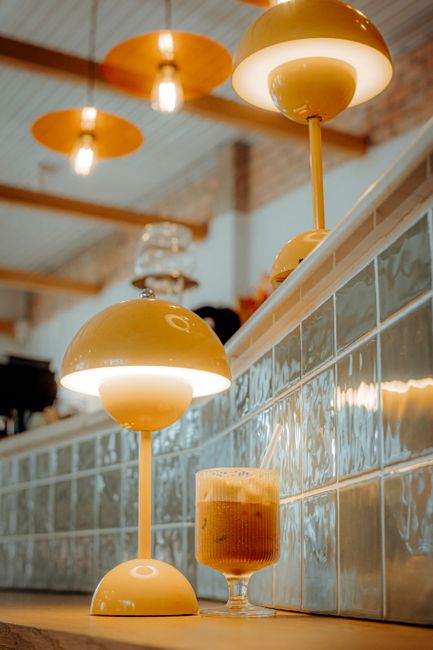 Warm ambient lighting in a stylish cafe setting with a glass of iced coffee.