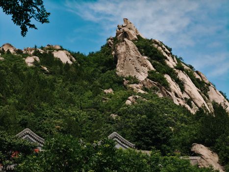 Explore a breathtaking rocky mountain and lush greenery under a clear blue sky.