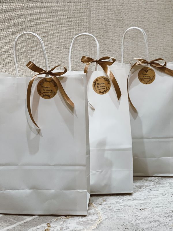 Elegant white gift bags with brown ribbons for wedding guests