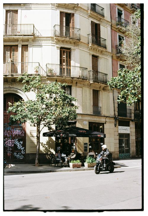 Free A bright day captures urban life with a motorcyclist on a city street. Stock Photo
