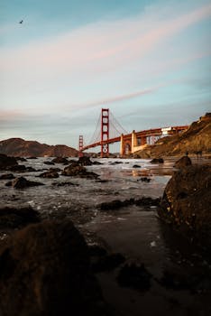 日落时分，金门大桥的壮丽景色，映衬着岩石海岸线与宁静的水域