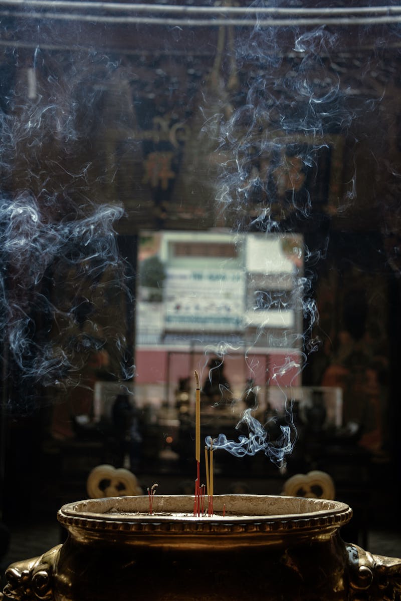 Serene image of incense sticks burning with smoke in a temple, evoking sacred prayer