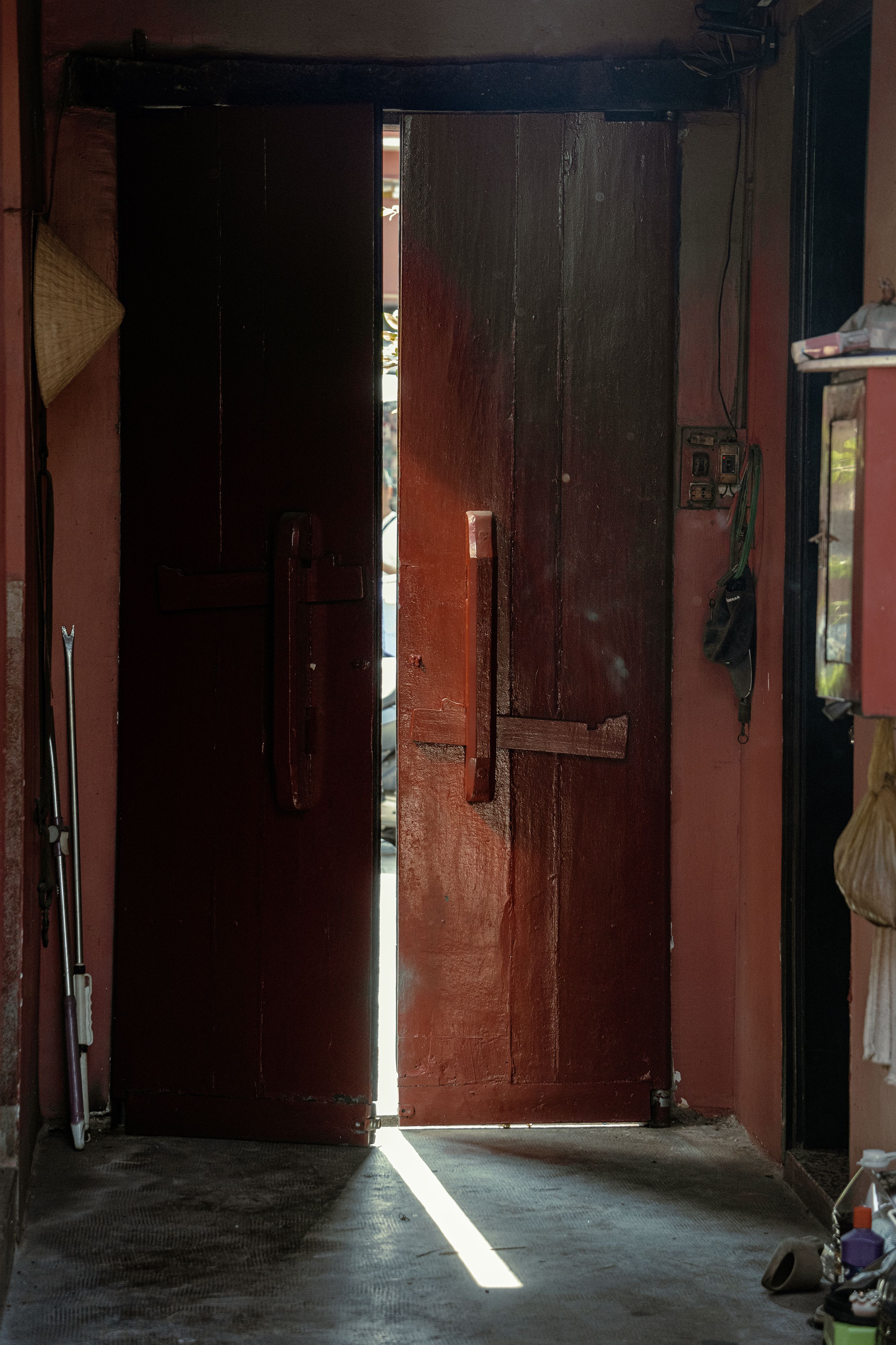 A wooden doorway partially open with a glimpse of light in a traditional setting in Ho Chi Minh City.