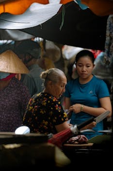 Elderly woman and others at a bustling Ho Chi Minh City wet market, Vietnam.