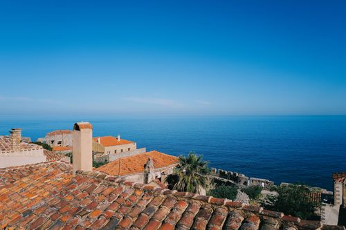 Free Beautiful Mediterranean tile rooftops with a stunning ocean view under a clear blue sky. Stock Photo