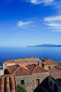 Capture of Mediterranean-style rooftops with a stunning sea view and clear blue sky.