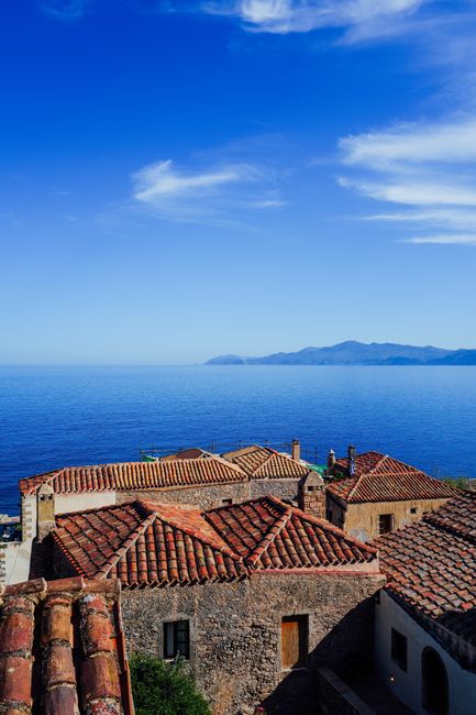 Capture of Mediterranean-style rooftops with a stunning sea view and clear blue sky.