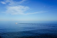 Serene Ocean View with Solitary Boat Under Blue Sky