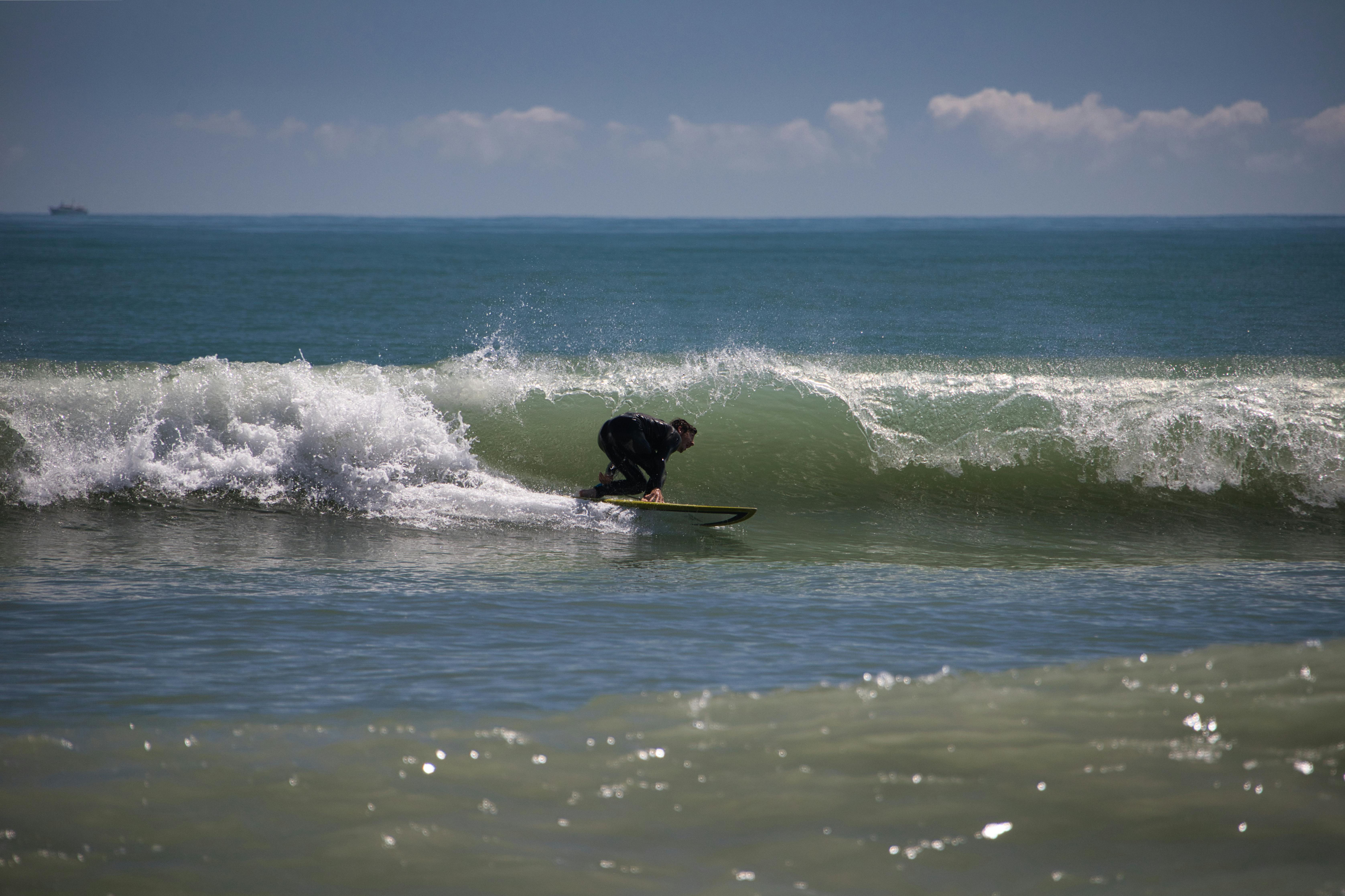 A surfer expertly rides a powerful wave on a sunny day at the beach.