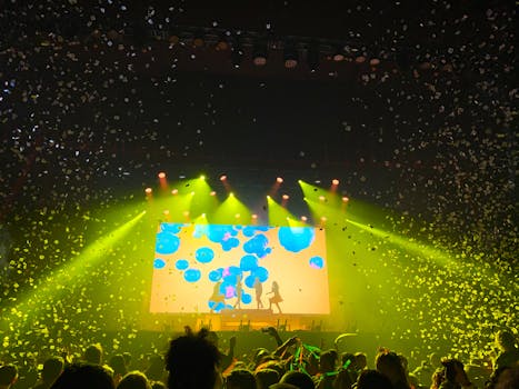 音乐会现场充满活力，灯光闪烁，五彩纸屑飞扬，人群正欣赏着精彩的表演