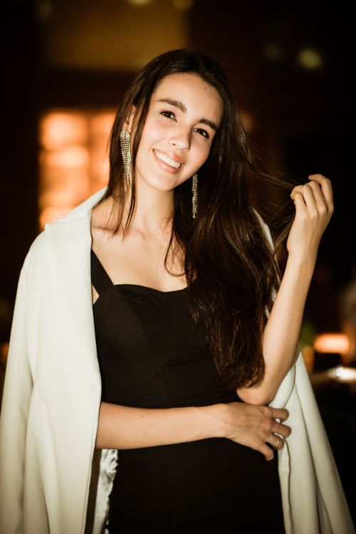 Free Charming woman wearing elegant black dress, smiling warmly indoors with ambient lighting. Stock Photo