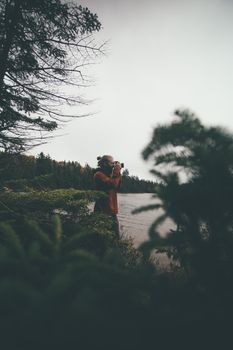 一位男摄影师在树林中捕捉到宁静的湖畔景色，周围郁郁葱葱