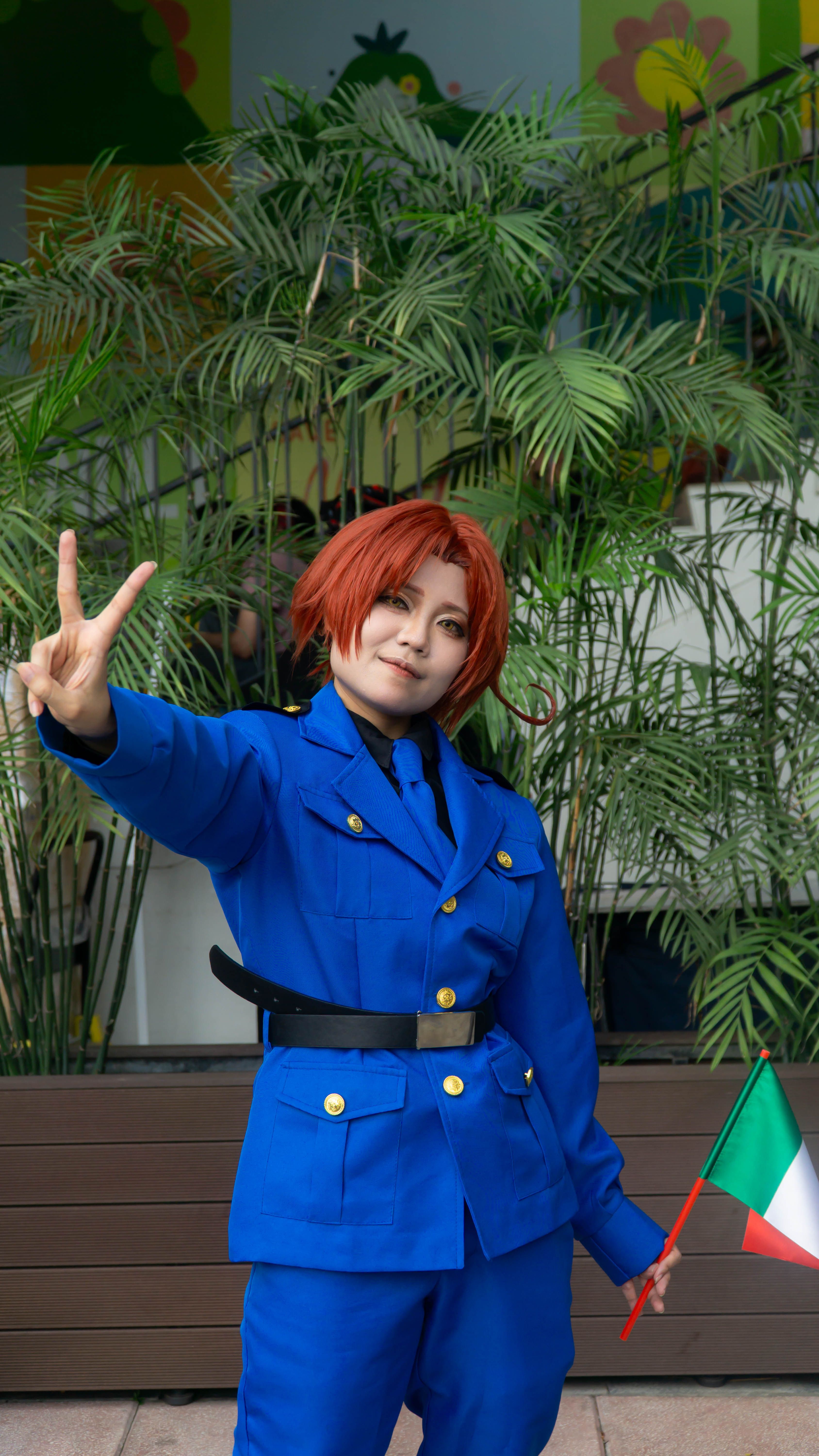 Cosplayer in Blue Costume Posing with Peace Sign