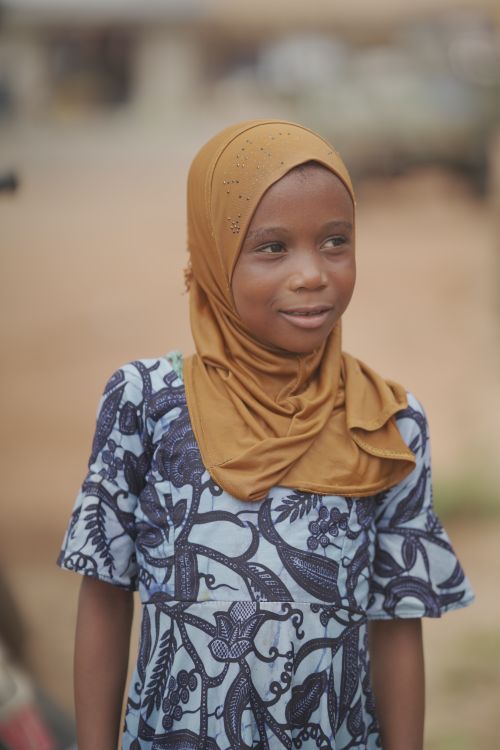 Free A young girl in a hijab smiles warmly, captured outdoors in Ghana. Stock Photo