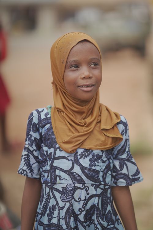Free A joyful young African girl wearing a hijab and traditional dress, captured outdoors in Ghana. Stock Photo