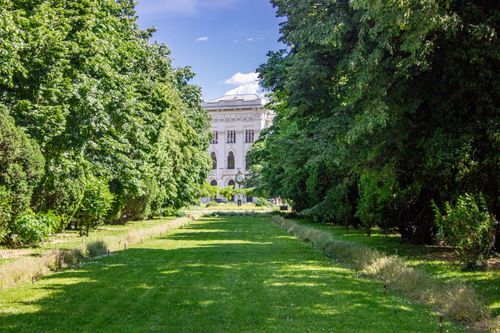 Free Charming view of a historic building framed by verdant trees and a manicured lawn. Stock Photo