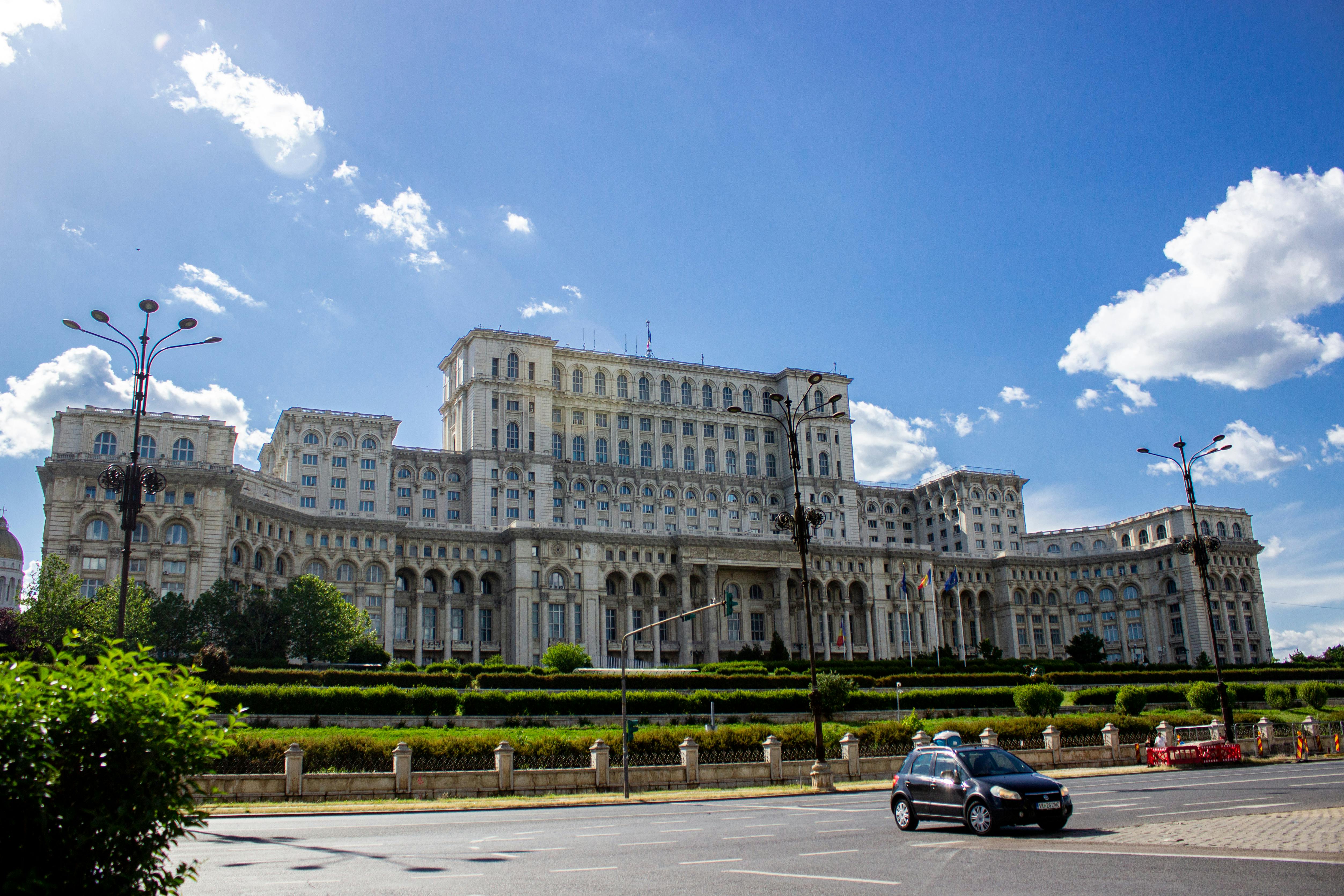 The Palace of the Parliament in Bucharest under a bright blue sky, showcasing its iconic architecture and grandeur.