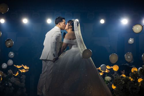Free Bride and groom share a romantic kiss on their wedding day surrounded by lights and balloons. Stock Photo