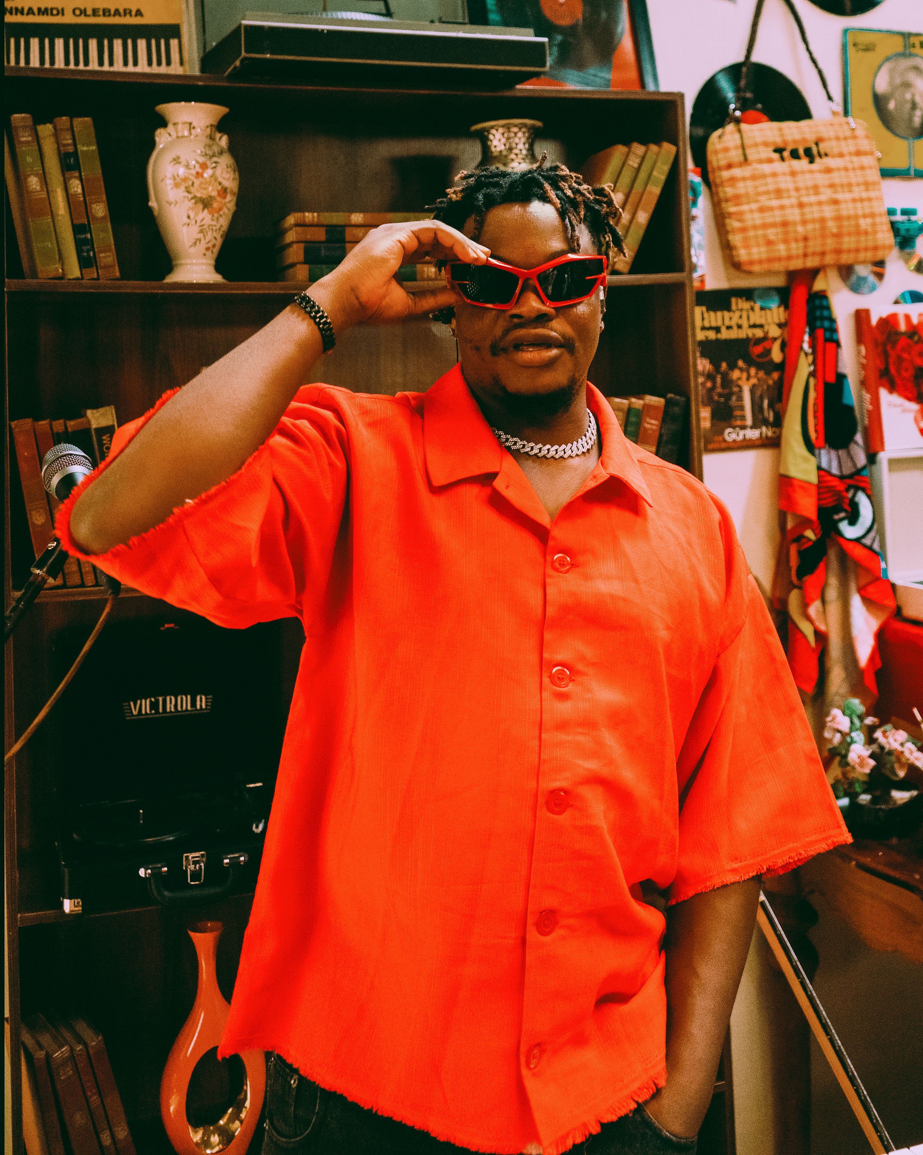 A fashionable man in red posing in a retro-style room with vintage decor.