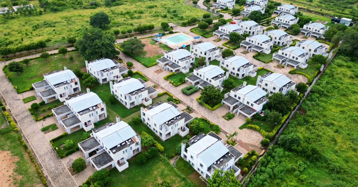 Aerial view of a modern residential neighborhood with white houses and green lawns.