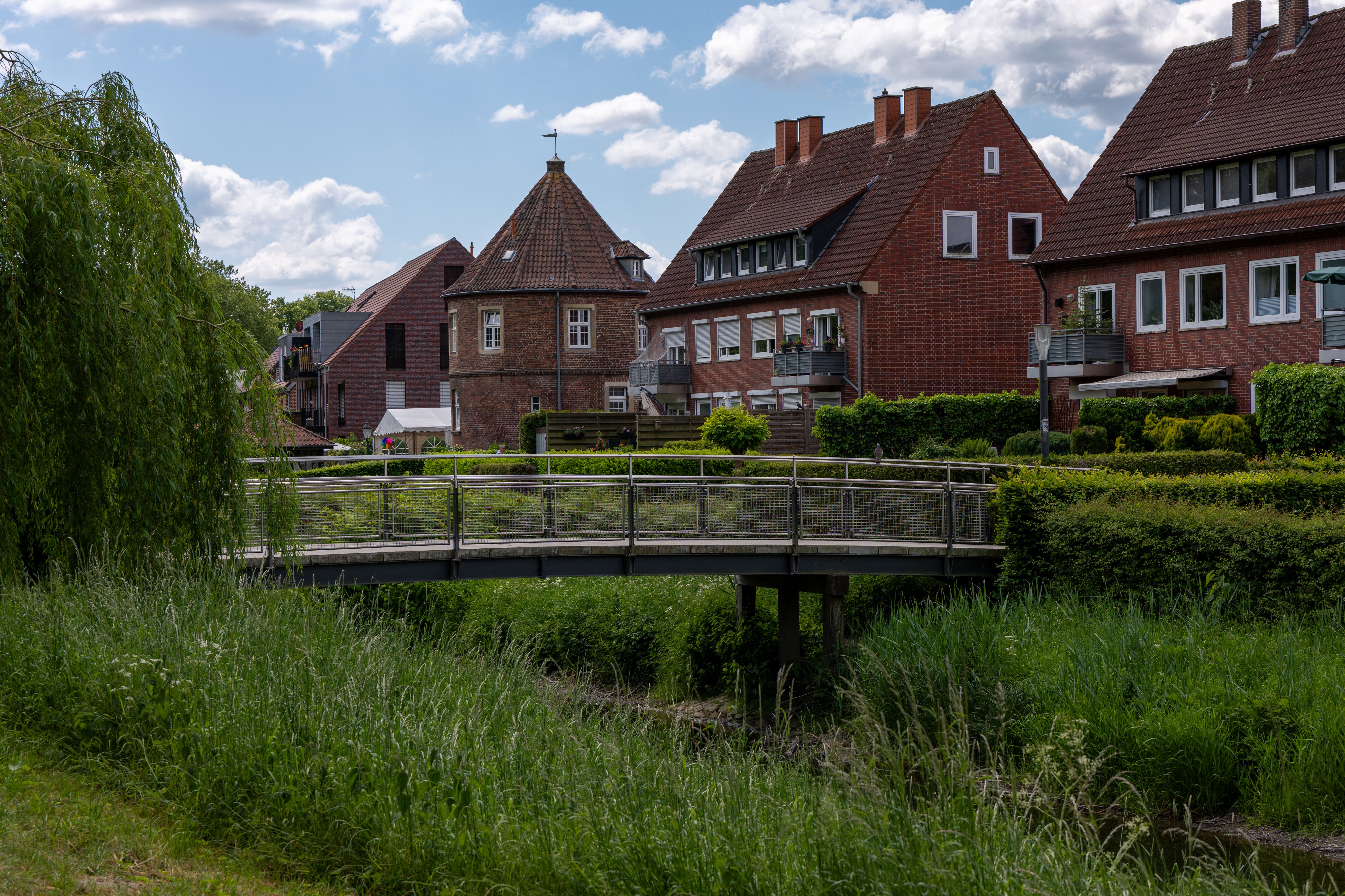 Scenic view of a European village featuring traditional houses and a quaint wooden bridge under a clear sky.
